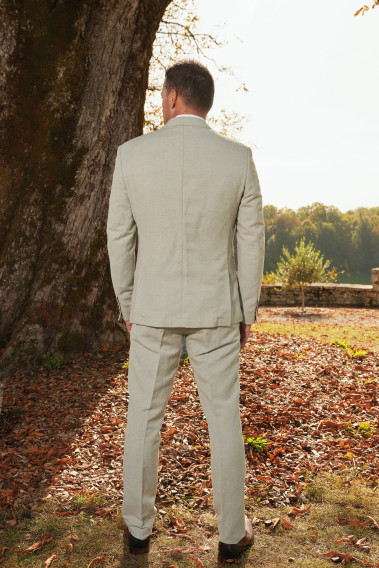 Homme de dos en costume GIORGIO couleur vert 3 pièces devant un arbre. Il porte des chaussures marrons.