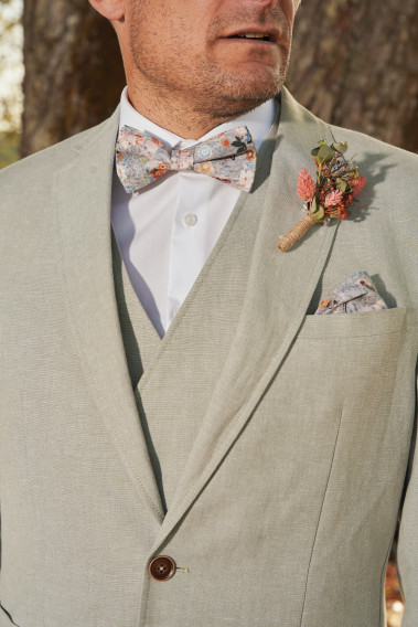 Costume GIORGIO vert. Plan sur le nœuds  papillon à motif floral et la poche assortie ainsi qu'un pins bouquet de fleur.