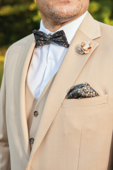 Costume SUAT beige sable. Plan sur le neoud papillon et la poche à motif noir.